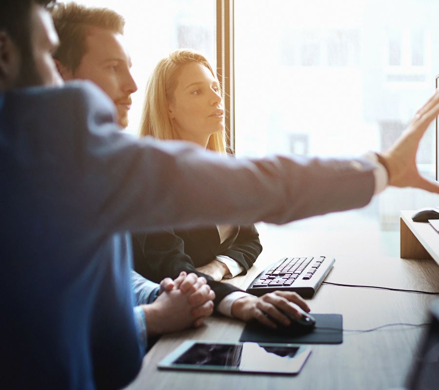 Stock image of business workers looking towards a computer monitor.